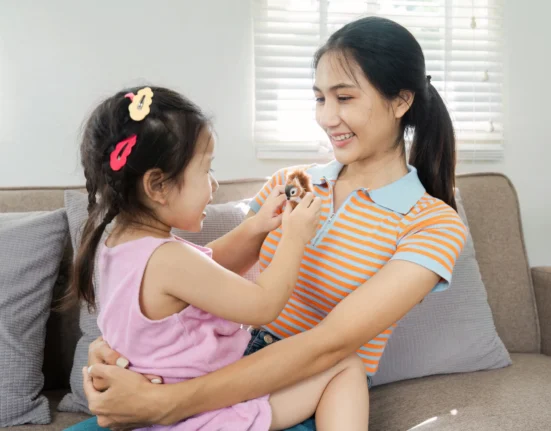 Ibu dan anak tersenyum dan bermain di sofa