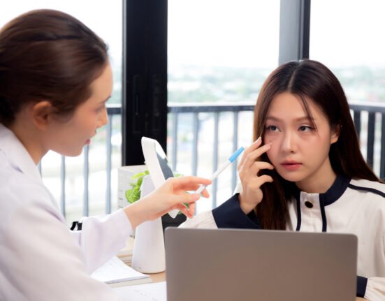 Female dermatologist carefully examining skin patient